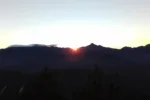 red rising sun shining through mountains