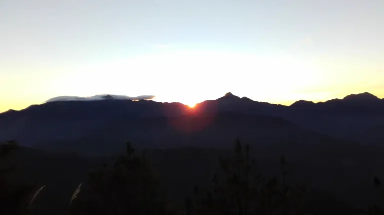 red rising sun shining through mountains